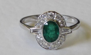 A lady's 18ct yellow gold dress ring set an oval cut emerald, 2 baguette cut diamonds to the shoulders and surrounded by diamonds