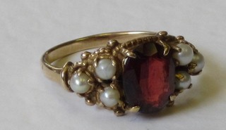 A gold dress ring set a red oval stone surrounded by pearls
