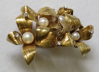 An 18ct gold brooch in the form of a flower head set pearls and diamonds