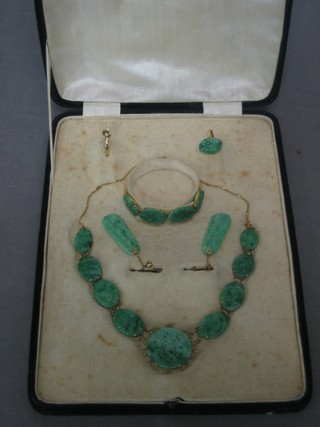 A suite of Oriental green pierced hardstone jewellery including necklace, bracelet, pair of earrings, dress ring and 1 other ring, all contained in a fitted case