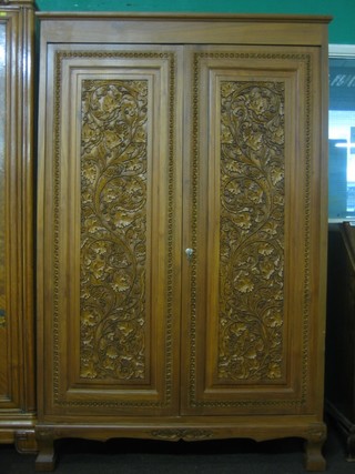 An Eastern carved hardwood wardrobe enclosed by a panelled door, the interior fitted a cupboard and raised on bracket feet 48"