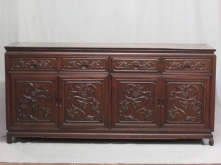 An Eastern carved hardwood sideboard fitted 4 drawers above cupboards enclosed by panelled doors, raised on scroll supports 71"