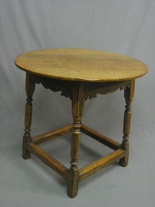 A circular honey oak occasional table, raised on turned and block supports 30"