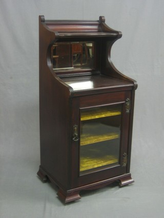 An Edwardian Art Nouveau mahogany music cabinet with raised back fitted a mirror, the base enclosed by a glazed panelled door and raised on ogee bracket feet 17"