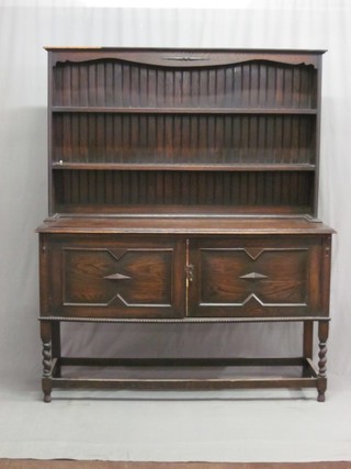 A dark oak dresser with raised back fitted 2 shelves above 2 cupboards enclosed by panelled doors, raised on spiral turned supports 59"