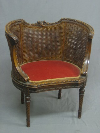 An Edwardian carved walnut tub shaped boudoir chair with double cane panels, raised on spiral carved supports