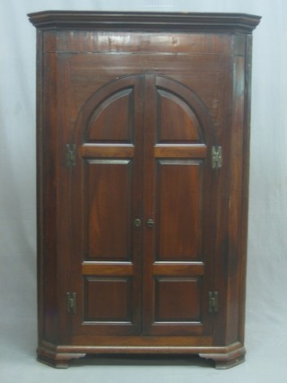 A Georgian mahogany corner cabinet with moulded cornice, the interior fitted shelves enclosed by an arch shaped panelled door, raised on bracket feet 38"