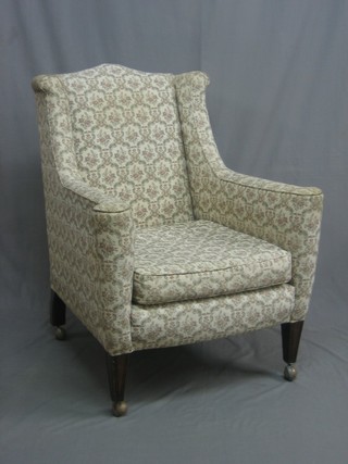 An Edwardian winged mahogany armchair upholstered in tapestry material