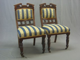 A pair of Edwardian carved walnut slat back dining chairs with carved pediments backs and upholstered seats, raised on turned and reeded supports