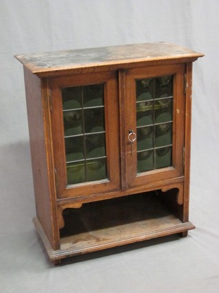 An Edwardian Art Nouveau walnut smoker's cabinet with fitted interior, enclosed by green glazed panelled doors 20"