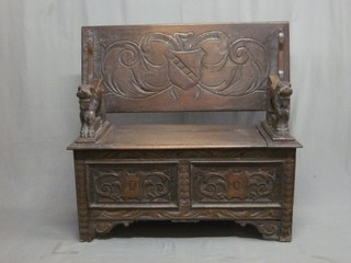A carved oak monks bench, the arms in the form of reclining lions 42"