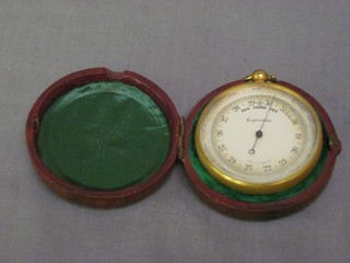 An aneroid pocket barometer contained in a gilt metal case with leather outer case