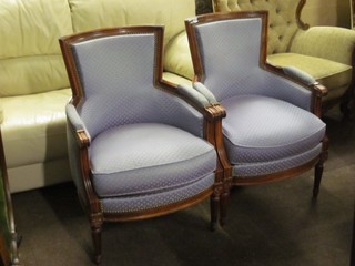 A pair of mahogany tub back armchairs upholstered in blue material, raised on turned and fluted supports