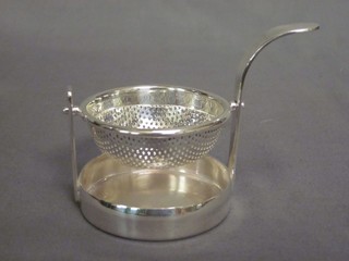 A modern silver plated tea strainer and stand