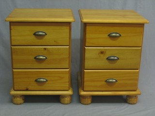 A pair of pine finished pedestal bedside chests of 3 long drawers raised on bun feet 18"
