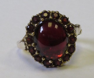 A 9ct gold dress ring set a cabouchon cut garnet, surrounded by garnets
