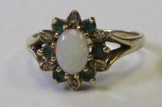 A lady's gold dress ring set an oval opal surrounded by emeralds and diamonds