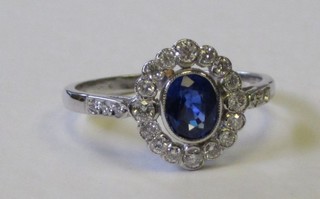 An 18ct white gold dress ring set an oval sapphire surrounded by diamonds and with 6 diamonds to the shoulders