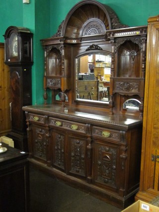 A Victorian heavily carved walnut sideboard with raised scallop shaped back having a mirror to the centre flanked by a pair of niches, the base fitted 1 long drawer flanked by 2 short drawers above a triple cupboard, raised on a platform base 72"