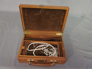 A leather jewellery box containing a strings of beads and a small collection of costume jewellery