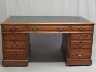 An Edwardian oak kneehole pedestal desk with inset green leather writing surface above 1 long and 8 short drawers 60"