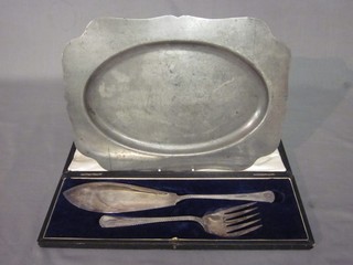 A pair of silver plated fish servers cased and an oval pewter dish