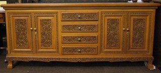 An Eastern carved hardwood sideboard fitted 4 long drawers flanked by cupboards, raised on bracket feet 79"