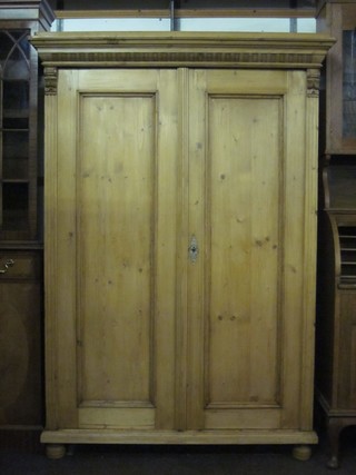 A Continental stripped and polished pine cabinet fitted shelves and enclosed by panelled doors, raised on bun feet 48"