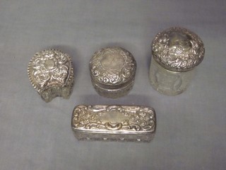 A rectangular silver pin jar with embossed silver lid, a horse shoe shaped cut glass dressing table jar and 2 circular jars with silver lids