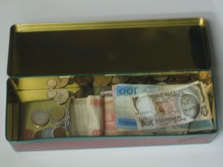 A collection of foreign coins and bank notes contained in a metal tin