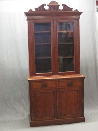 An Edwardian walnut bookcase on cabinet, the upper section with carved cornice, the interior fitted adjustable shelves enclosed by glazed panelled doors, the base fitted 2 drawers above double cupboards, raised on platform base 41"