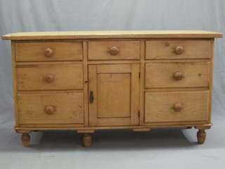 A pine sideboard/dresser base, fitted numerous drawers and with cupboard to the centre, raised on bun feet with tore handles 59"
