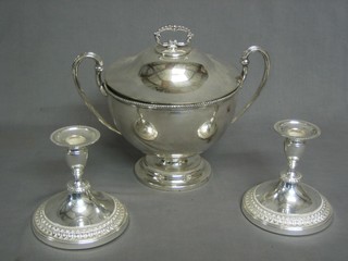 A silver plated twin handled soup tureen and cover and a pair of silver plated candlesticks