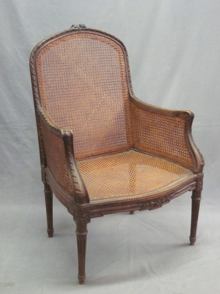 A pair of French carved walnut Bergere library chairs with carved cresting rail and double cane panels to the side, raised on turned and fluted supports