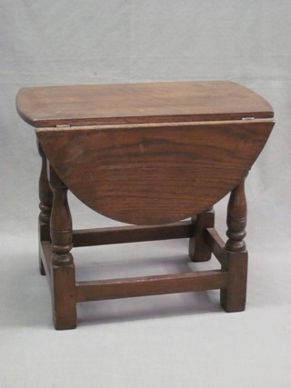 An oval drop flap coffee table, raised on turned and block supports 21"
