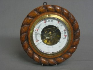 An aneroid barometer with enamelled dial contained in a carved oak case 9"
