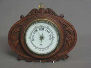 An aneroid barometer with porcelain dial contained in a carved oak case