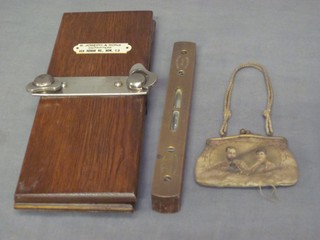 A small fabric purse decorated a portrait of King George V and Queen Mary, a brass spirit level marked 1621, an oak tie press marked R Joseph & Sons Outfitters