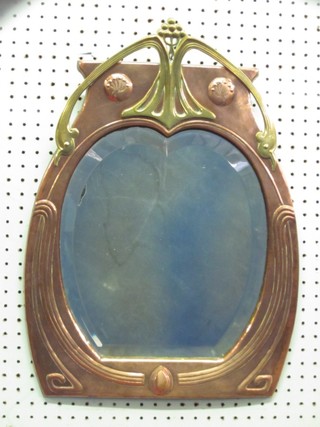 An Art Nouveau shaped bevelled plate wall mirror contained in an embossed copper and brass frame 21"