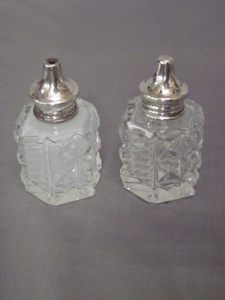 A pair of octagonal cut glass salt and pepper pots with silver lids 