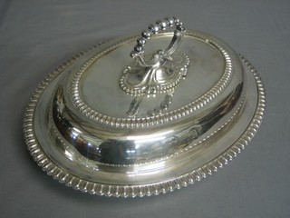 An oval silver plated entree dish and cover with beadwork border