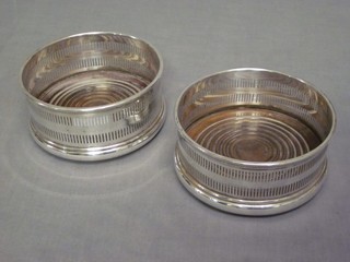 A pair of circular pierced silver plated bottle coasters