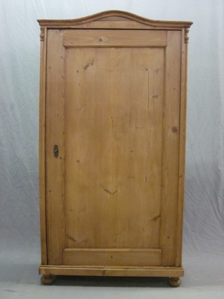 A Continental stripped and polished pine cupboard with arched top, shelved interior and enclosed by a panelled door, raised on bun feet 37"