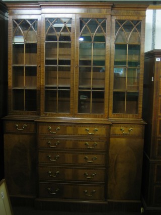 A Georgian style mahogany breakfront bookcase on cabinet, the upper section with moulded cornice, the interior fitted adjustable shelves enclosed by astragal glazed doors, the base fitted a brushing slide and 5 long drawers, flanked by a pair of double cupboards 54"