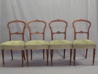 A set of 4 Victorian carved walnut spoon back chairs with shaped mid rails and upholstered seats