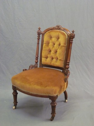 A Victorian walnut show frame nursing chair upholstered in orange material, raised on turned and fluted supports