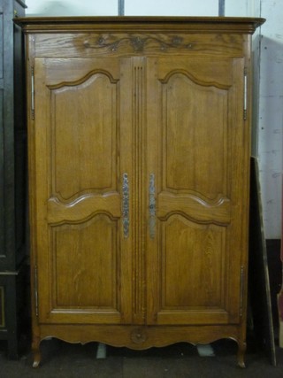 A Continental elm wardrobe enclosed by a pair of panelled doors, raised on cabriole supports 43"