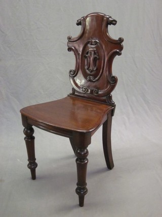 A Victorian mahogany hall chair with shield shaped back and solid seat, raised on turned supports