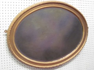 An oval bevelled plate wall mirror contained in a decorative gilt frame 27"