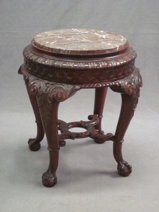 An Eastern circular carved hardwood jardiniere stand with pink veined marble top, raised on cabriole ball and claw supports, 18"